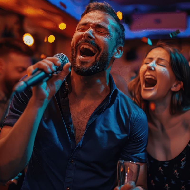 Homme et femme chantant passionnément au micro, les yeux fermés, bouche grande ouverte, lors d'une soirée karaoké festive.